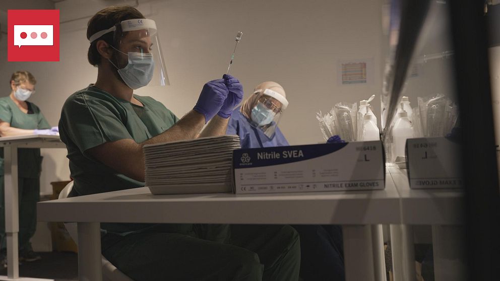 Läkare fyller en kanyl med vaccin från en liten burk.