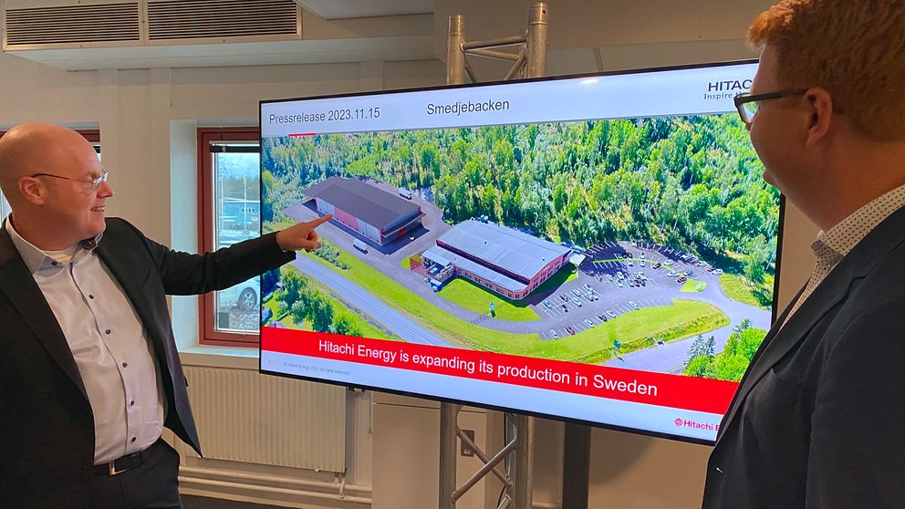 Vd:n för Hitachi Energy Sverige pekar på en bild av den nya fabriken på en tv-skärm.