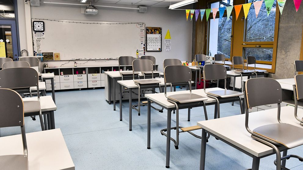 En bild på ett klassrum, utan några personer. Stolarna hänger på bordet, det finns en whiteboard i bakgrunden.