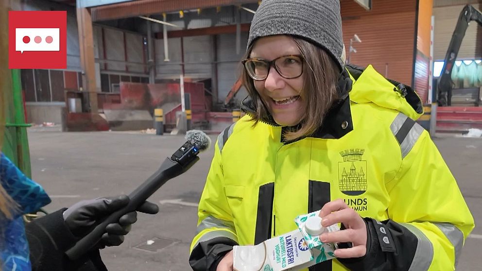 Reporter intervjuar person som håller en förpackning inne på en sopstation.