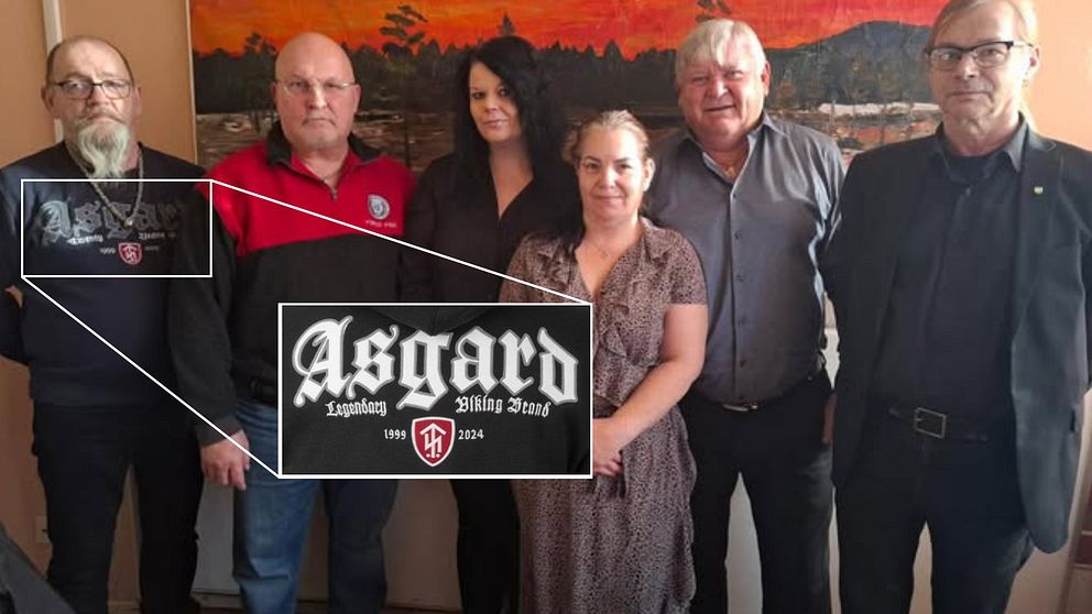 Sex vuxna står framför en tavla. Inzoomning visar texten ”Asgard” på en tröja.