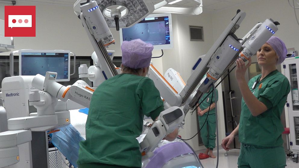 På bilden syns två personer som står vid operationsroboten.