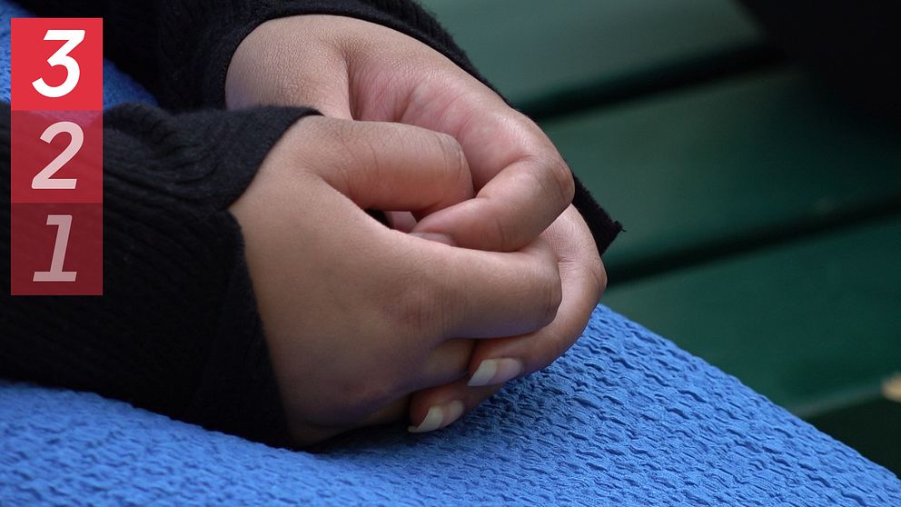 kvinna med knäppta händer som sitter på en parkbänk