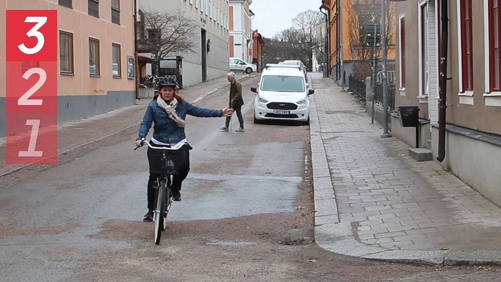 Kvinna på cykel som vinkar.