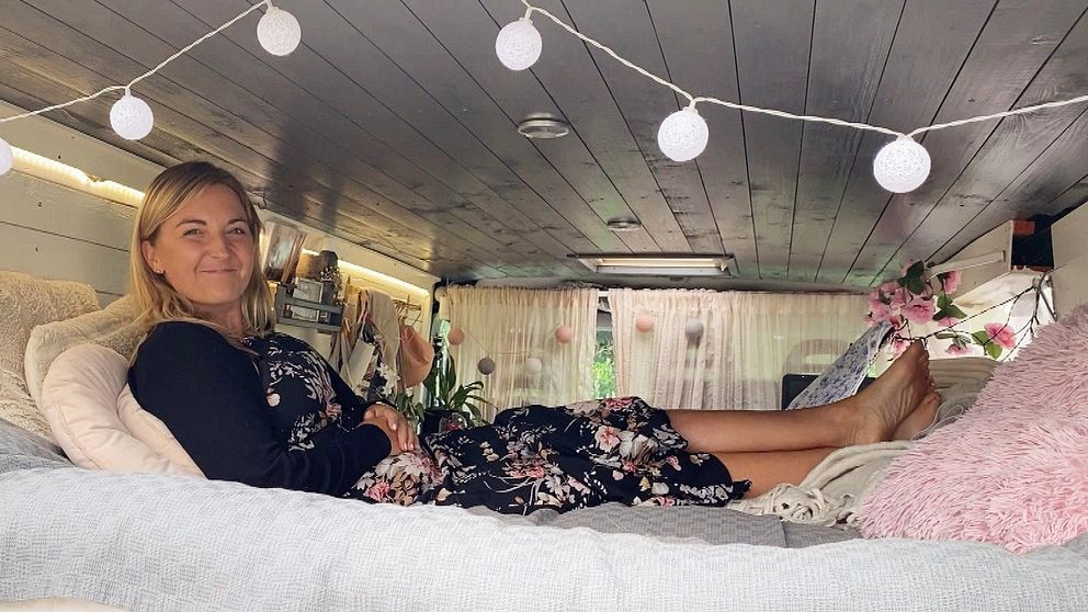 Kvinna ligger på säng i ombyggd van