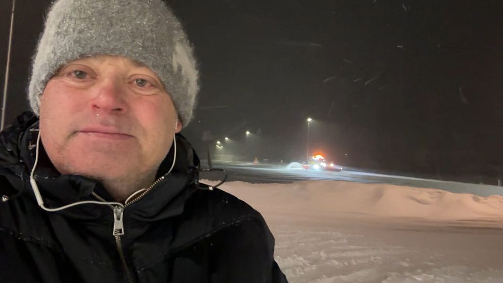 En man i grå mössa står ute i snöoväder