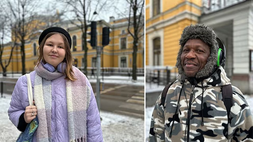 Två personer står utomhus på en snötäckt gata. Den vänstra personen bär en lila jacka och en scarf, medan den högra personen har på sig en camouflage-mönstrad jacka med en huva. I bakgrunden syns en byggnad med gul fasad och trädkronor utan löv.