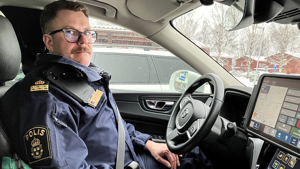 En man med glasögon och mustasch, polisen Thomas Nordström, sitter i polisuniform i en polisbil i Avesta.