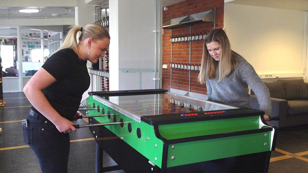 Två flickor spelar fotbollsspel på fritidsgård