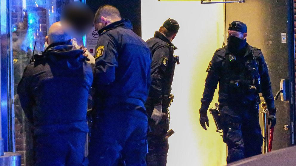 Flera poliser utanför en byggnad i nattbelysning