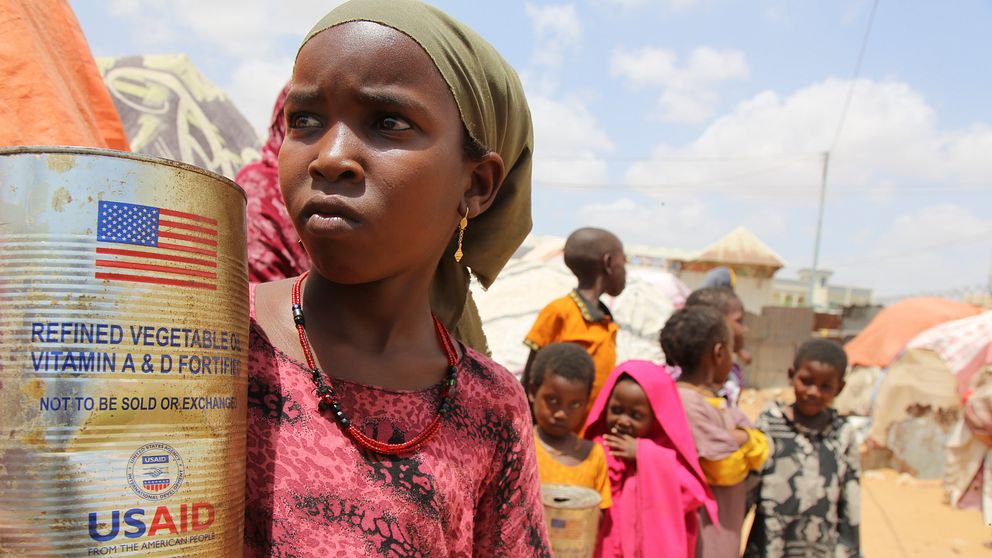 Barn i flyktingläger, ett barn håller en burk med biståndsmat från USAID.