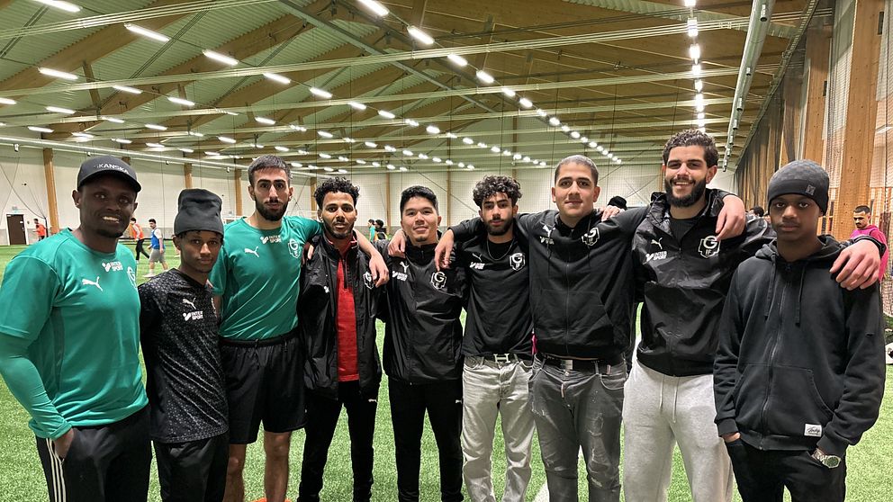 Nio killar som är ledare för nattfotbollen i Örnsköldsvik står i en fotbollshall och håller varandra om axlarna.