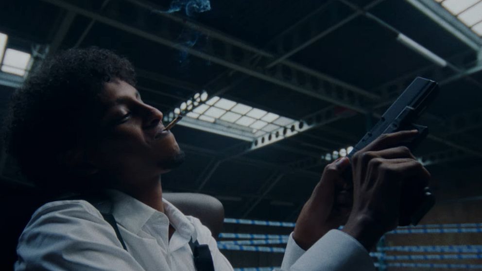Rapparen Yasin med ett vapen i en musikvideo.