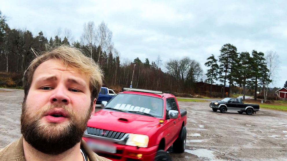 En man står framför tre a-traktorer som kör iväg från en grusig parkeringsplats.