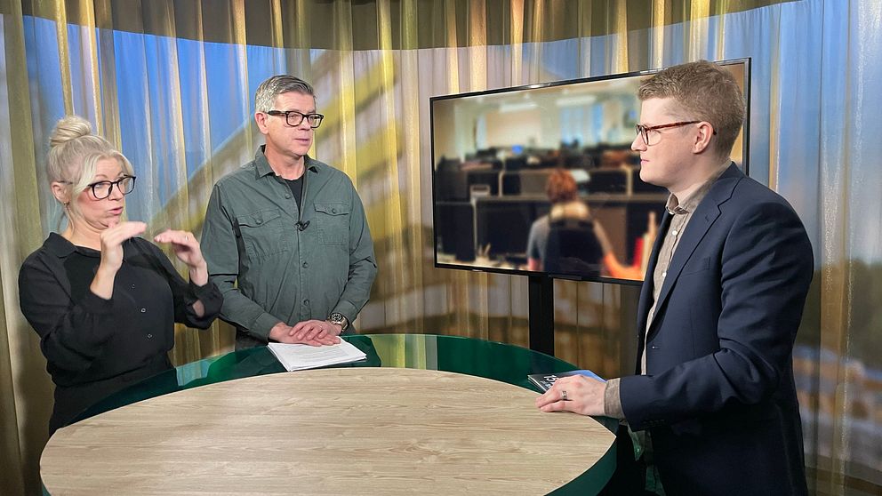 Gästen Lars Arrhenius står i en studio med programledaren Magnus Bergevin och en teckenspråkstolk.