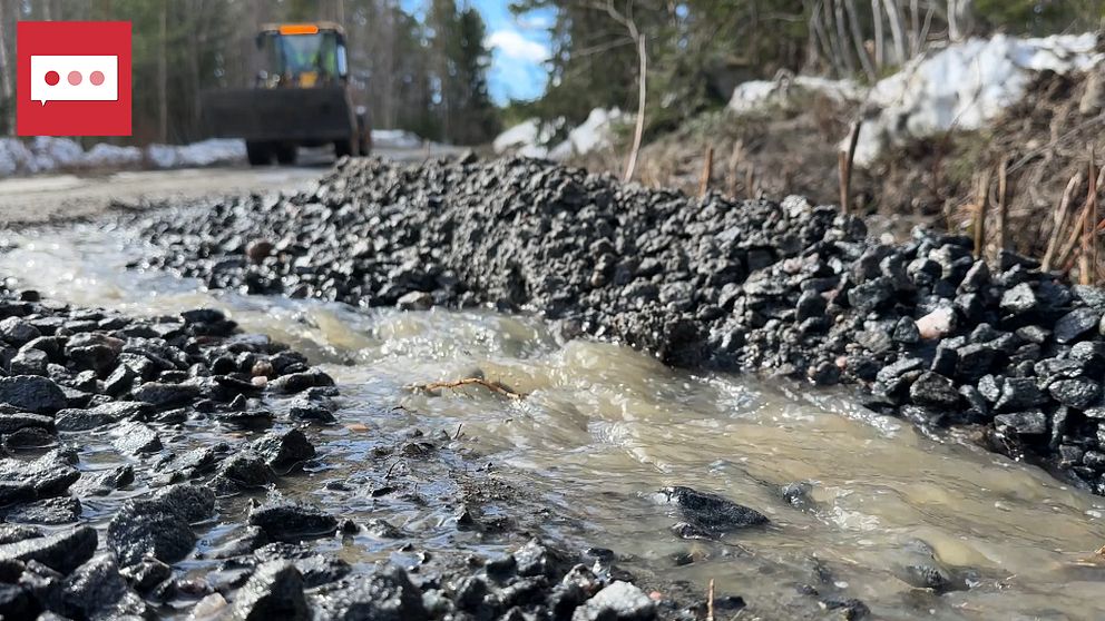 En traktor kör längs en grusväg där vatten rinner i förgrunden.