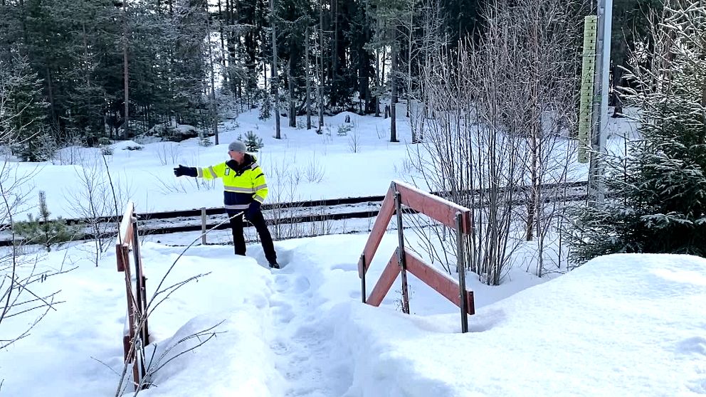 en man som står bredvid en järnväg och pekar.