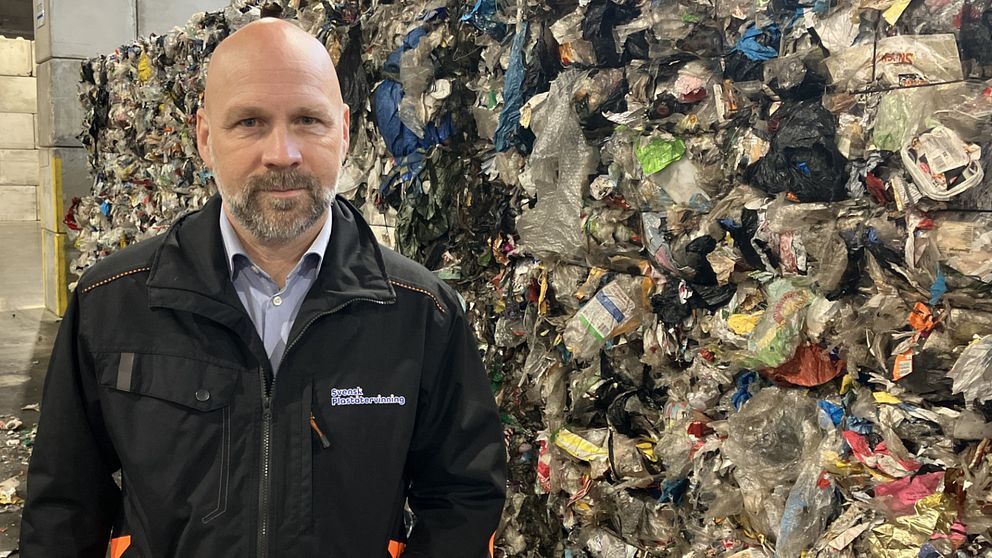 Mattias Philipsson, vd för Svensk pappersåtervinning i Motala, står framför ett sopberg av plast.