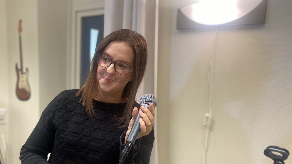 Matilda sjunger med en mikrofon i handen i en studioinredning.
