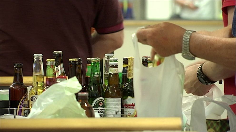 Genrebild, en person packar ner ölflaskor i en påse på systembolaget.