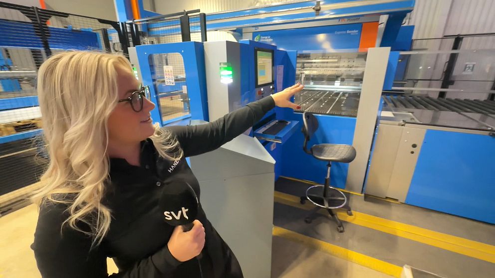 Ung tjej visar helautomatiserad maskinfabrik