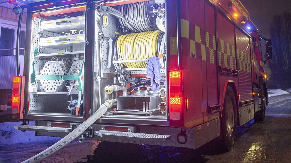 Brandbilens bakdörrar är öppna och bile har blinkande blåljus.