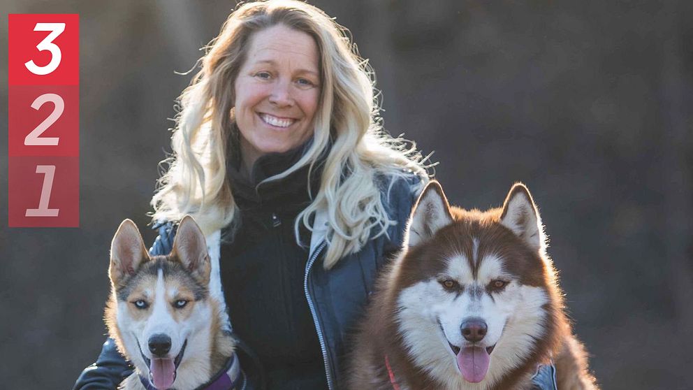 Hundpsykologen Tess Erngren utomhus som kramar om två hundar