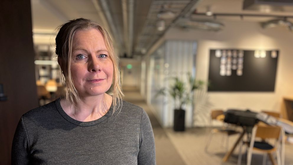Person står i en modern kontorsmiljö med suddiga konturer i bakgrunden.