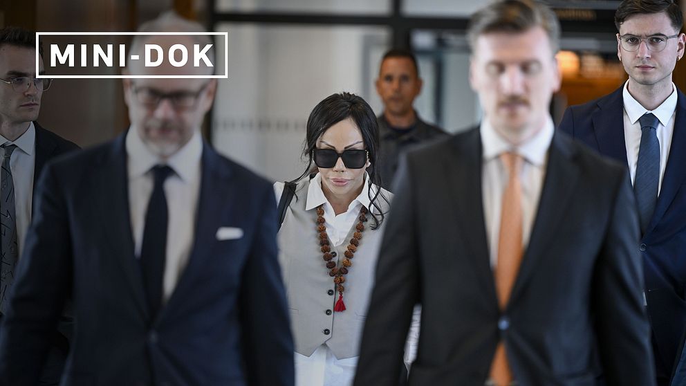 Flera personer i kostym och en kvinna med halsband och stora solglasögonen promenerar i tingsrätten.