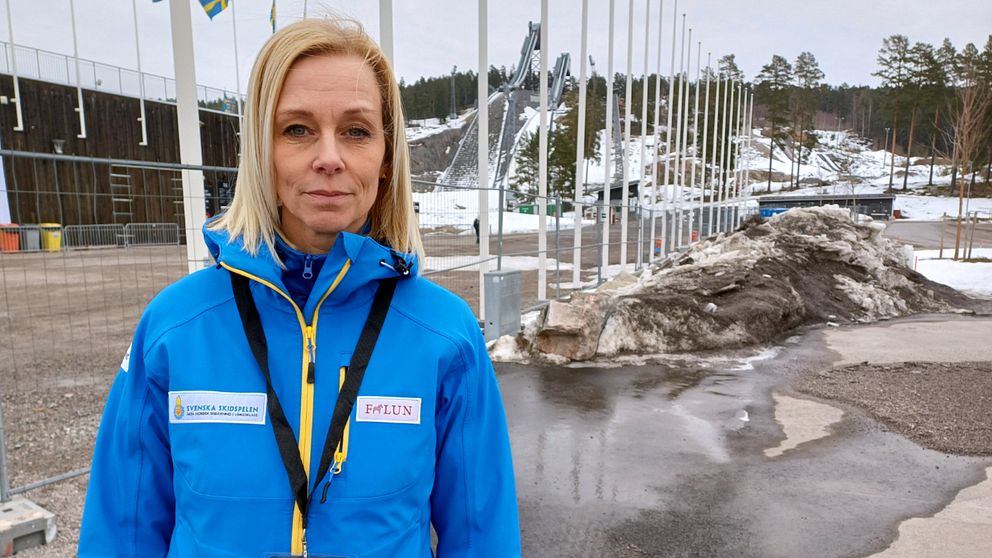Ulrika Back, vd för Svenska Skidspelen, står utanför Lugnets skidstadion med tomma flaggstänger i bakgrunden