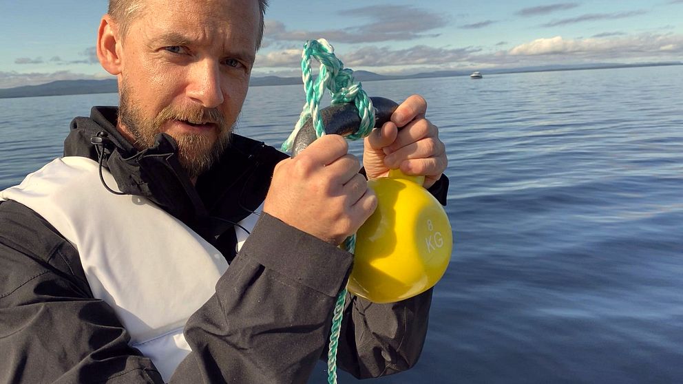 Reporter håller upp kettlebell i ett rep.