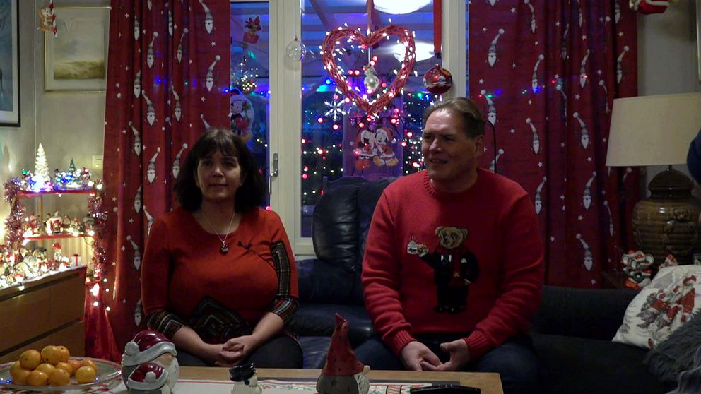 Et par som sitter i et hus i julestil, iført hver sin julegenser