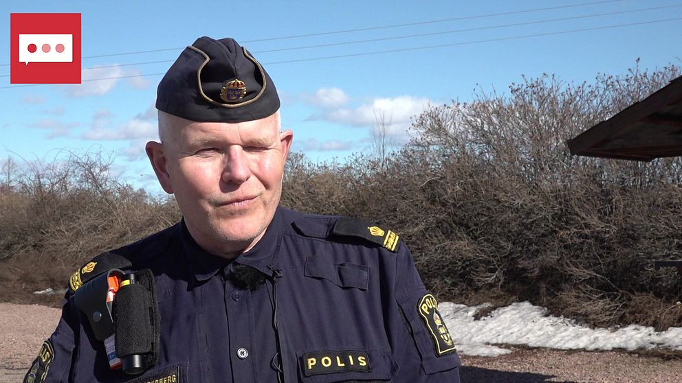 Polis som står och kisar in i solen.