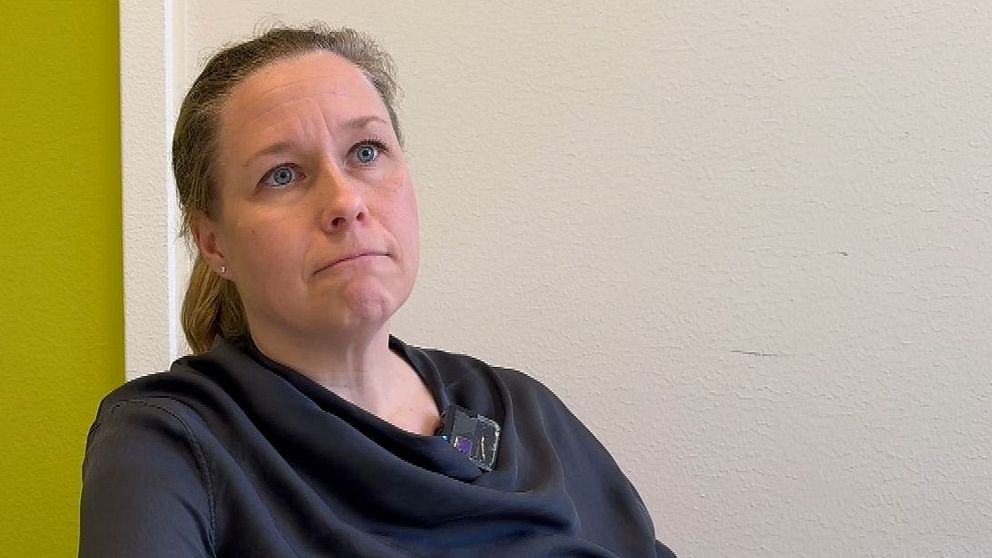 Gymnasiechef vid Peder Skrivare gymnasieskola Sofia Rådström Andersson vid bord med händer knäppta. Grön vägg med en tavla i bakgrunden.