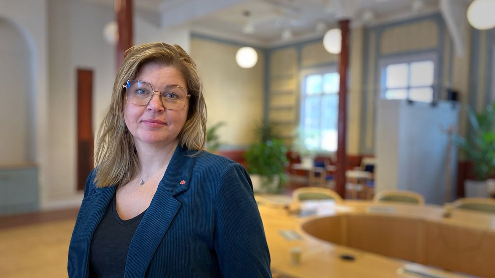 Therese Kärngard, kvinna i glasögon och blå kavaj står i en samlingslokal i Östersund.