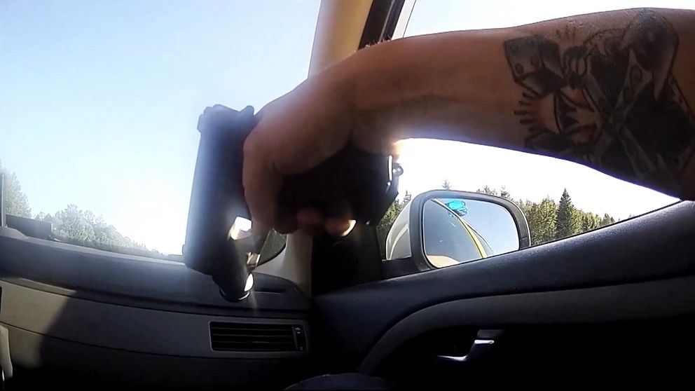 Hand som håller i en pistol inuti en bil.