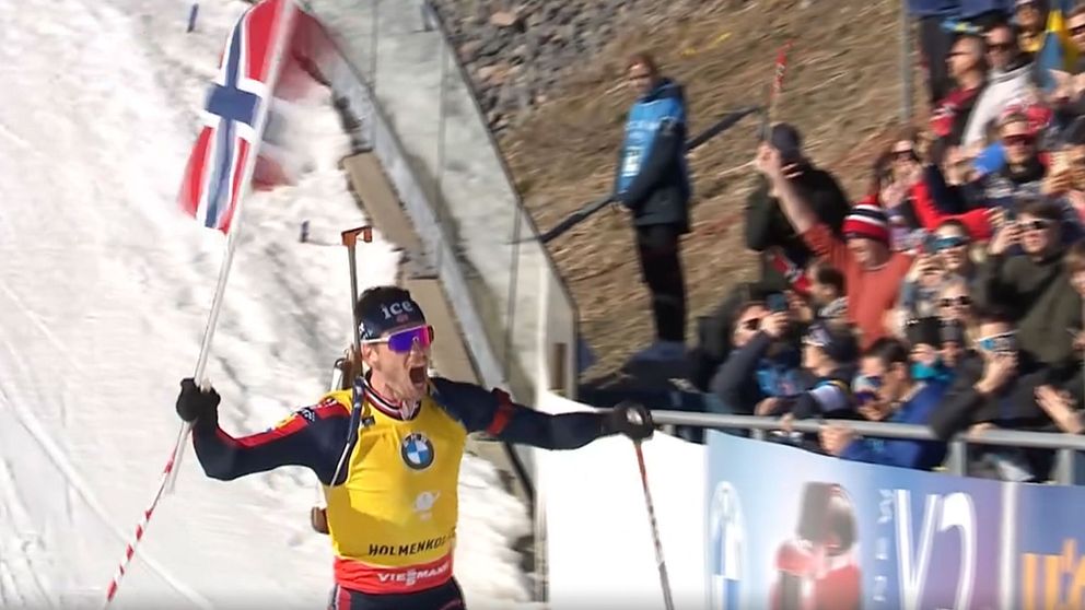 Skidåkare firar vid mållinjen med norsk flagga inför jublande publik.