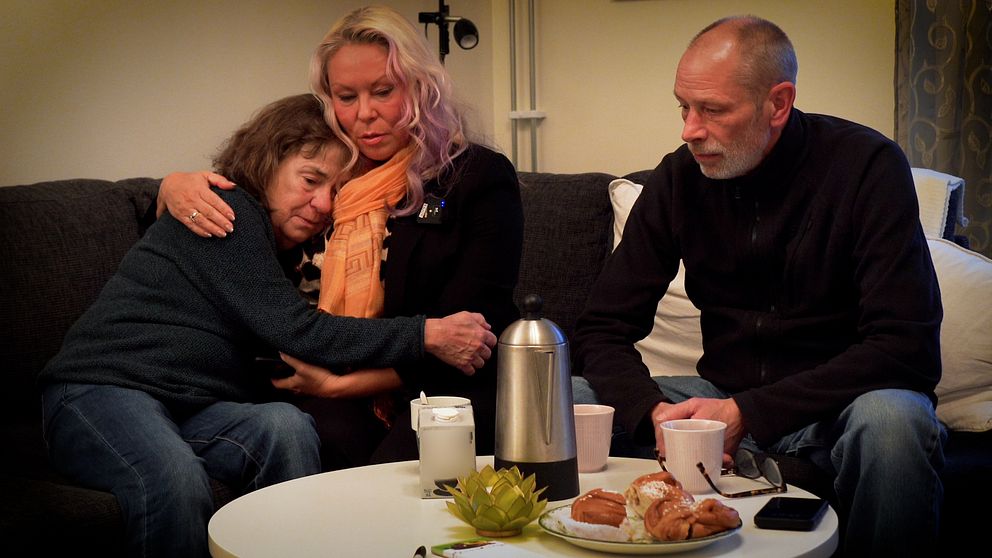 En grupp sitter framför ett bord med kaffe och bullar. De ser nedstämda ut.