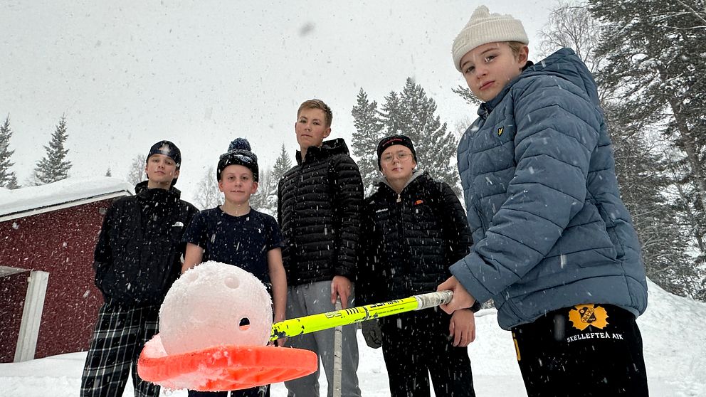 Fyra killar står bredvid varandra. En håller i en innebandyklubba där det vilar en boll på bladet.