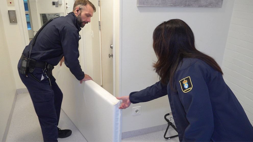 Två personer i personalen på Halmstad anstalt möblerar om och flyttar en vit madrass.