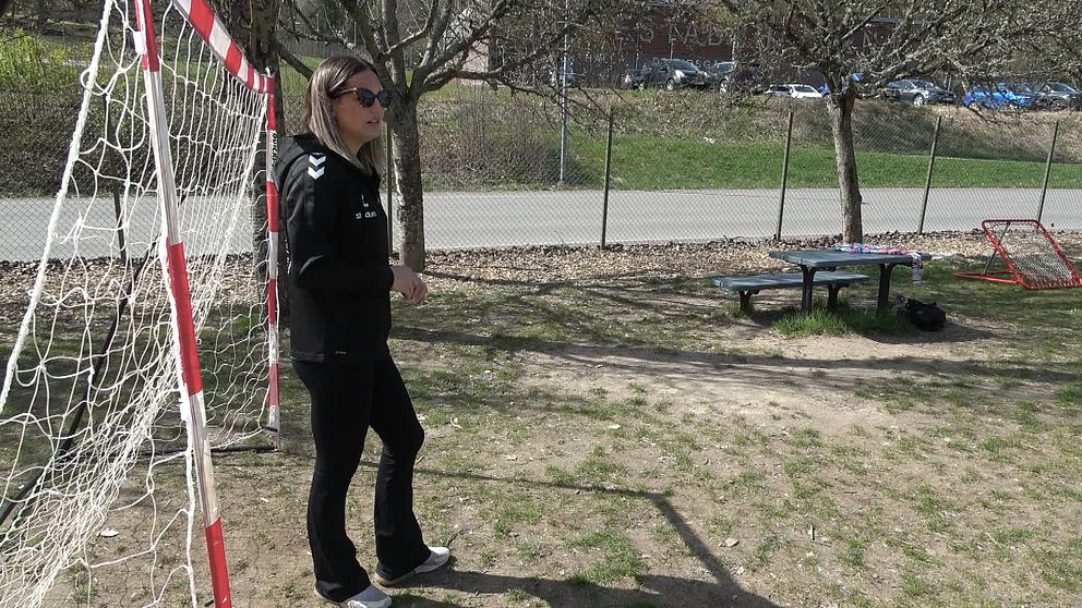 Kvinna står i solglasögon och vaktar ett fotbollsmål.