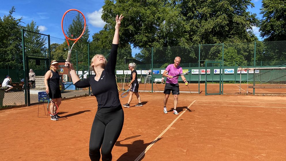 Tennisspelare kastar upp bollen och ska precis slå med sitt racket.