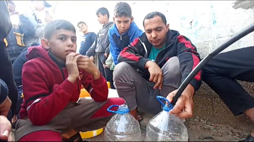 Människor i gaza häller upp vatten i flaskor.