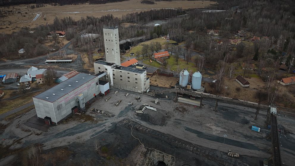 Flygbild av ett gammalt industriområde omgivet av skog och fält.