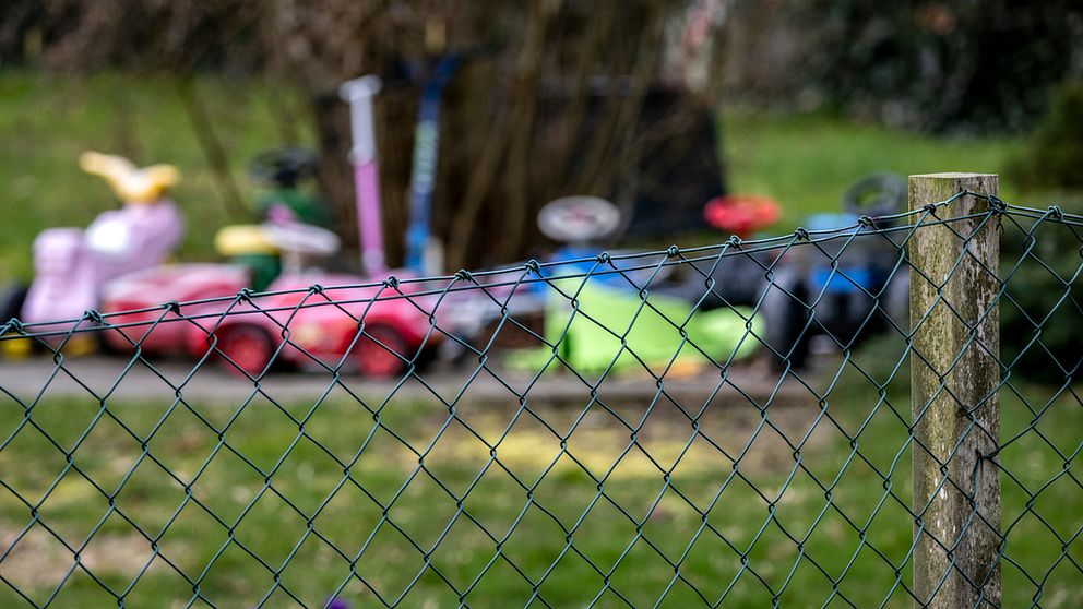 Leksaker på en trädgård bakom ett staket.