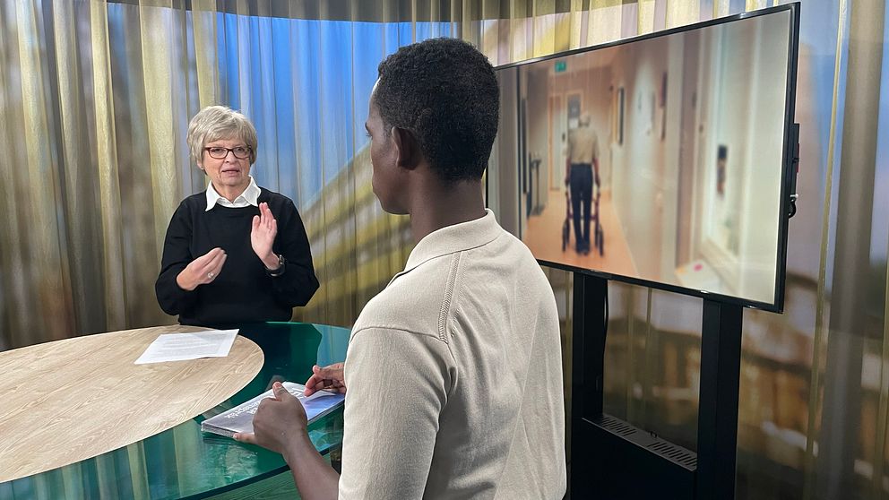 Sveriges dövas pensionärsförbund står och tecknar i en studio. Ryggtavlan syns på programledaren Abdi Mohamed och i skärmen bredvid dem visas en korridor med en äldre man som går med en rollator.