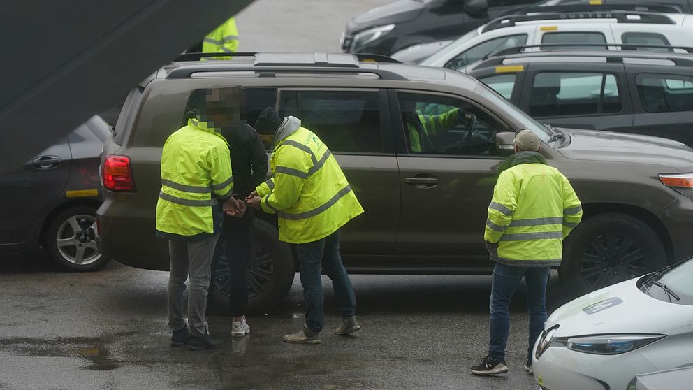 En man i handfängsel framför en bil