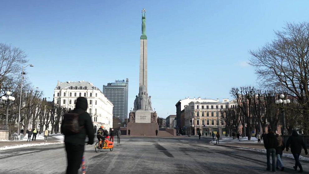 Torgplats med människor somn går och cyklar i Lettlands huvudstad Riga.