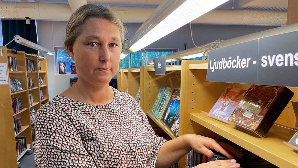 bibliotekschefen Towe Karlsson fingrar på några ljudböcker i Strängnäs bibliotek