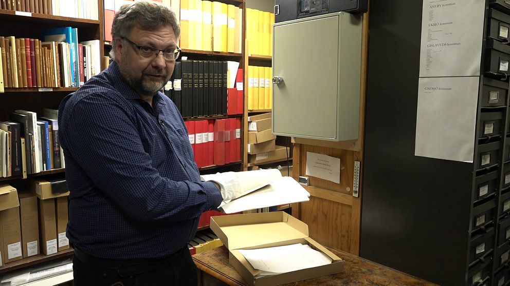 Arkivarien Henrik Johansson står i Jönsköpings Läns Museums arkiv och håller några av John Bauers brev i sina händer.